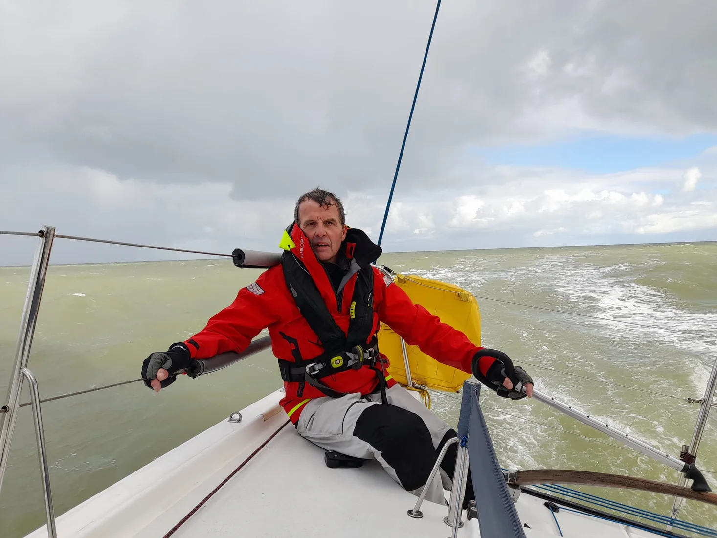 Amaury à la barre au large, le sac à voile jaune à côté de lui