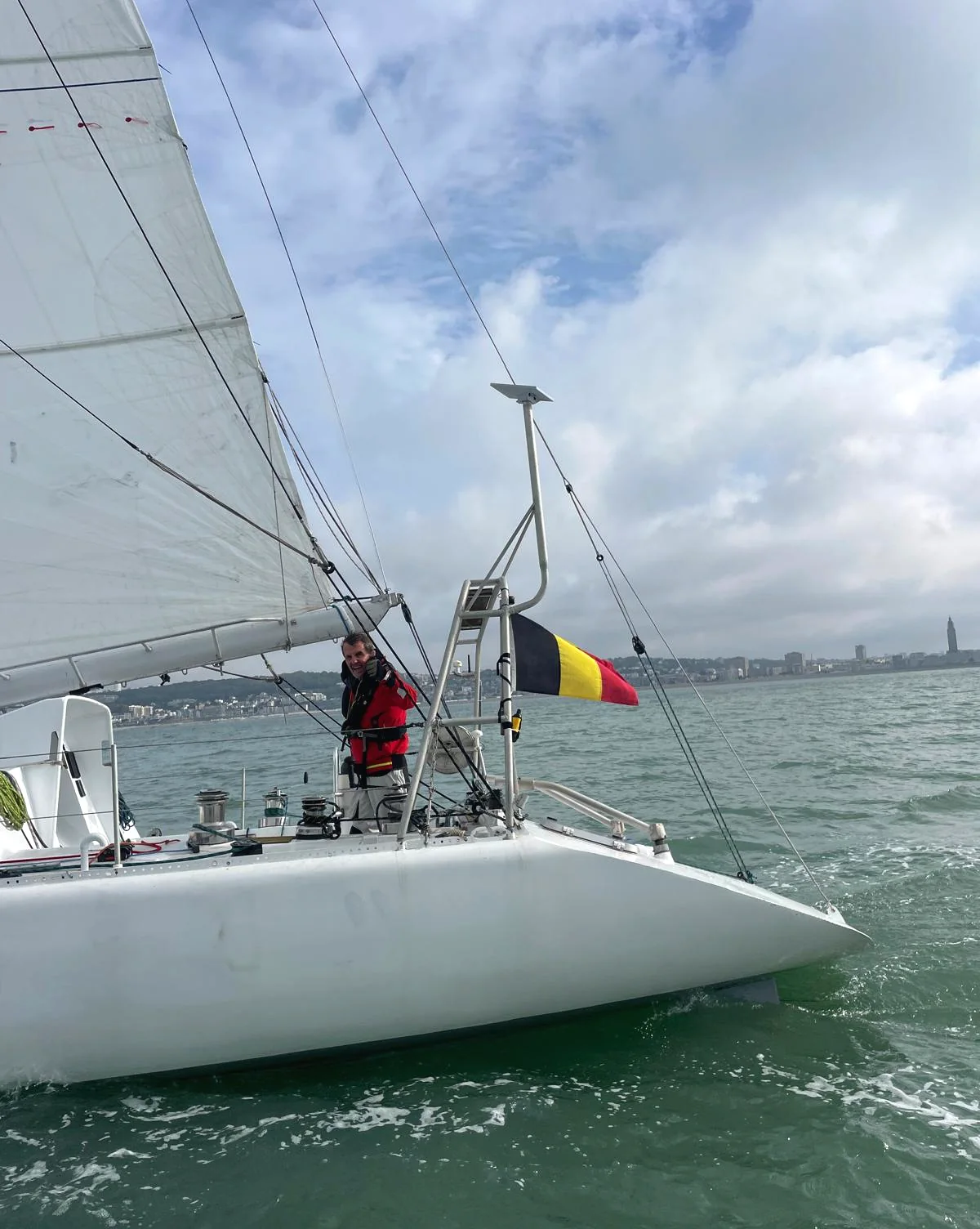 Amaury à la barre, vu par-dessus l’étrave, le drapeau belge à côté de lui