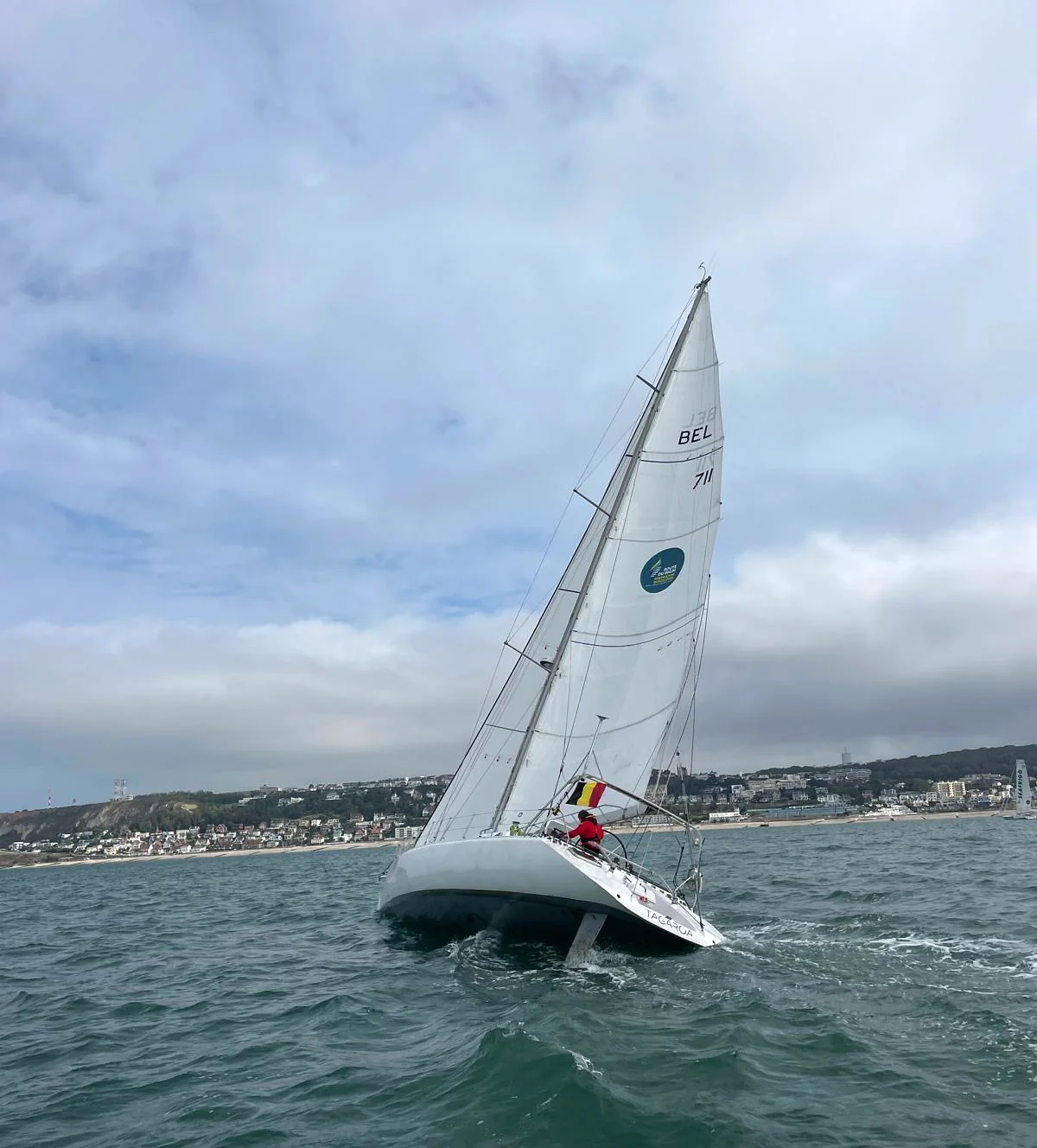 Tagaroa gîte, le numéro de voile BEL 711 sur la grand-voile et la côte en arrière-plan