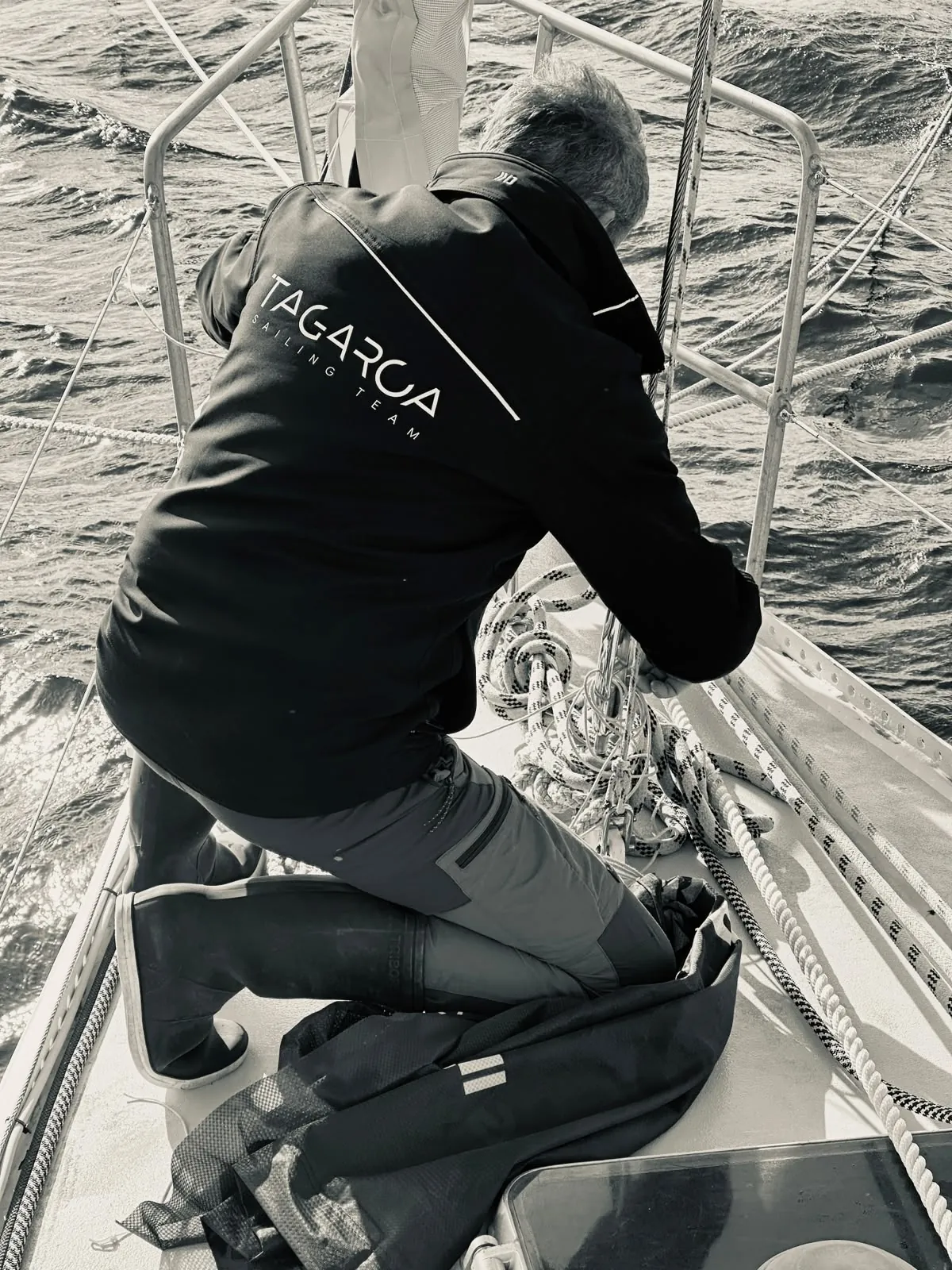 Amaury à genoux sur le pont avant de Tagaroa, entouré par la mer